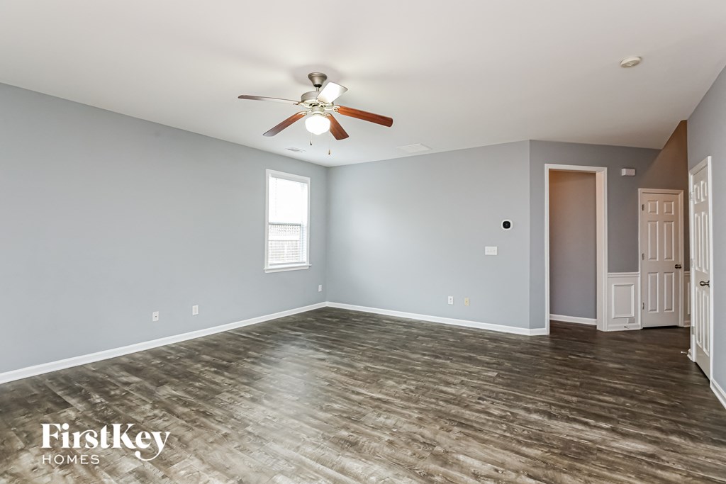 A spacious room with a ceiling fan and wooden flooring.