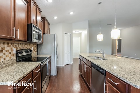 A kitchen with brown cabinets and granite countertops.