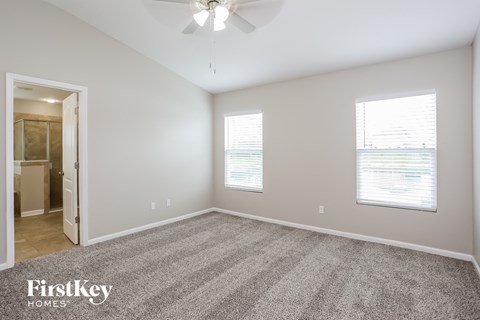 A spacious room with a carpeted floor and a ceiling fan.
