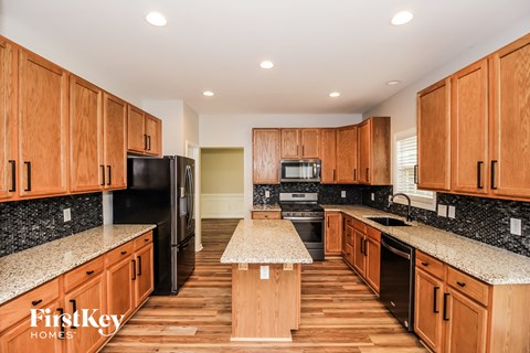 a kitchen with wooden cabinets and granite counter tops and black appliances