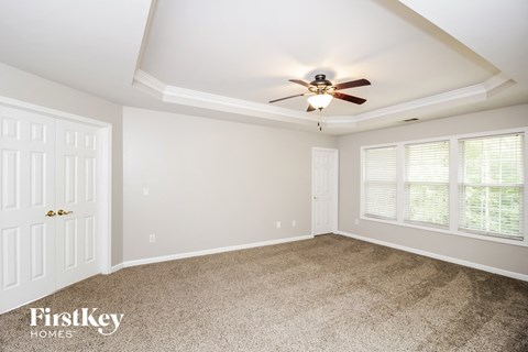 the master bedroom has a ceiling fan and a carpeted floor