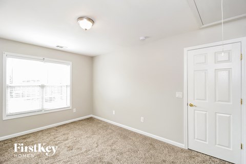 a bedroom with white door and carpet and a window