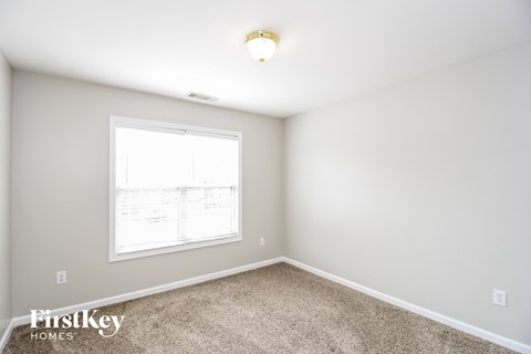 a bedroom with a window and a carpeted floor