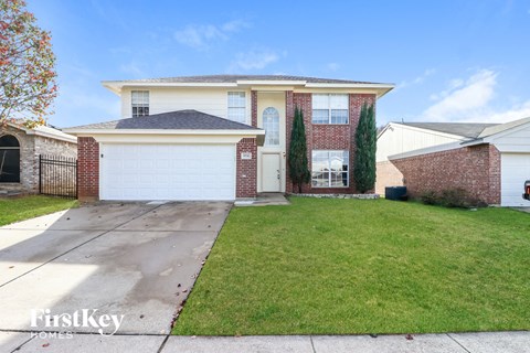 the front of a house with a driveway and lawn