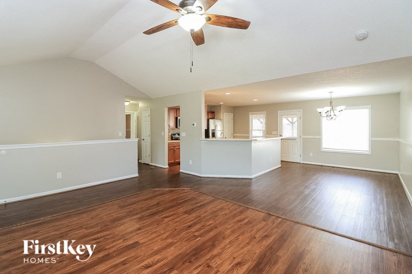 an empty living room with wood flooring and a ceiling fan