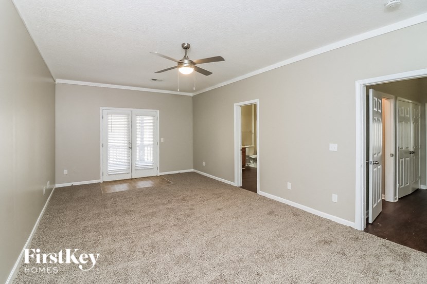 a spacious living room with carpet and a ceiling fan