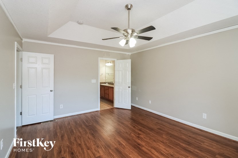 an empty living room with wood flooring and a ceiling fan