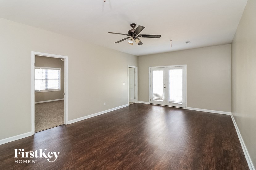 an empty living room with wood flooring and a ceiling fan