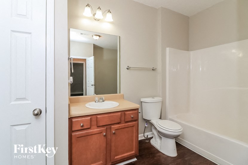 a bathroom with a toilet sink and mirror and a shower
