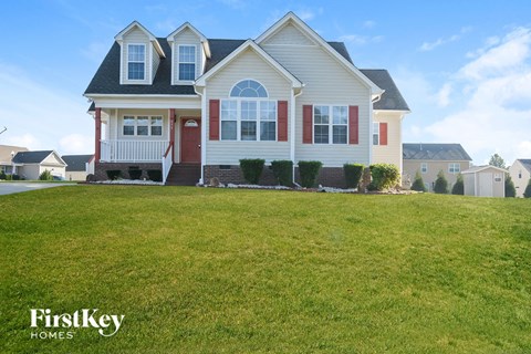 a white house with red shutters and a lawn