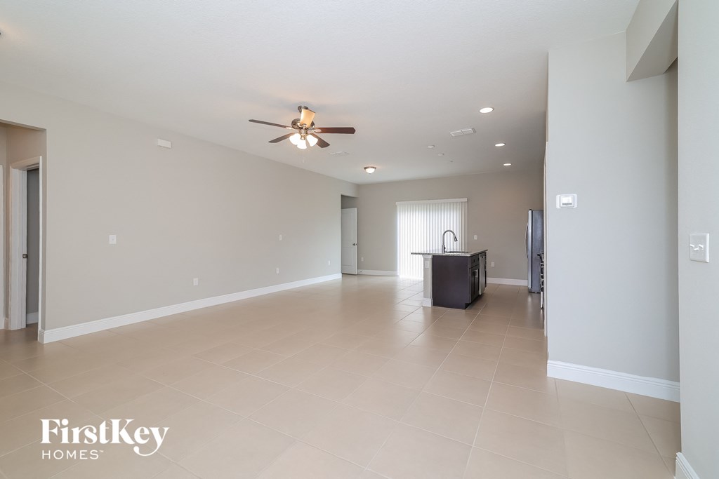 A spacious empty room with a ceiling fan and a cabinet.