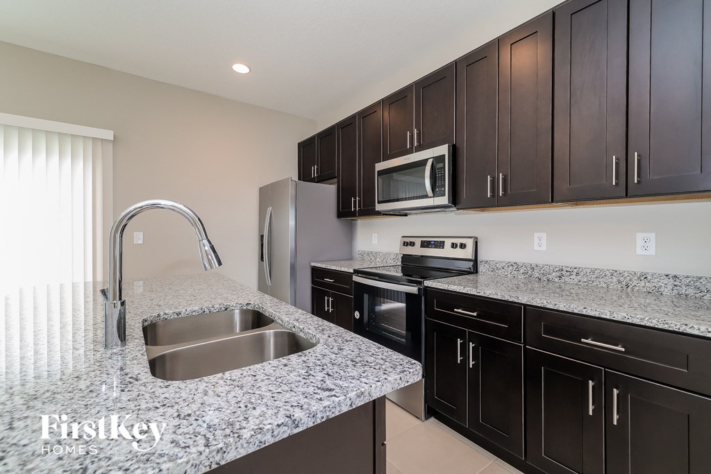 A kitchen with granite countertops and a stainless steel sink.