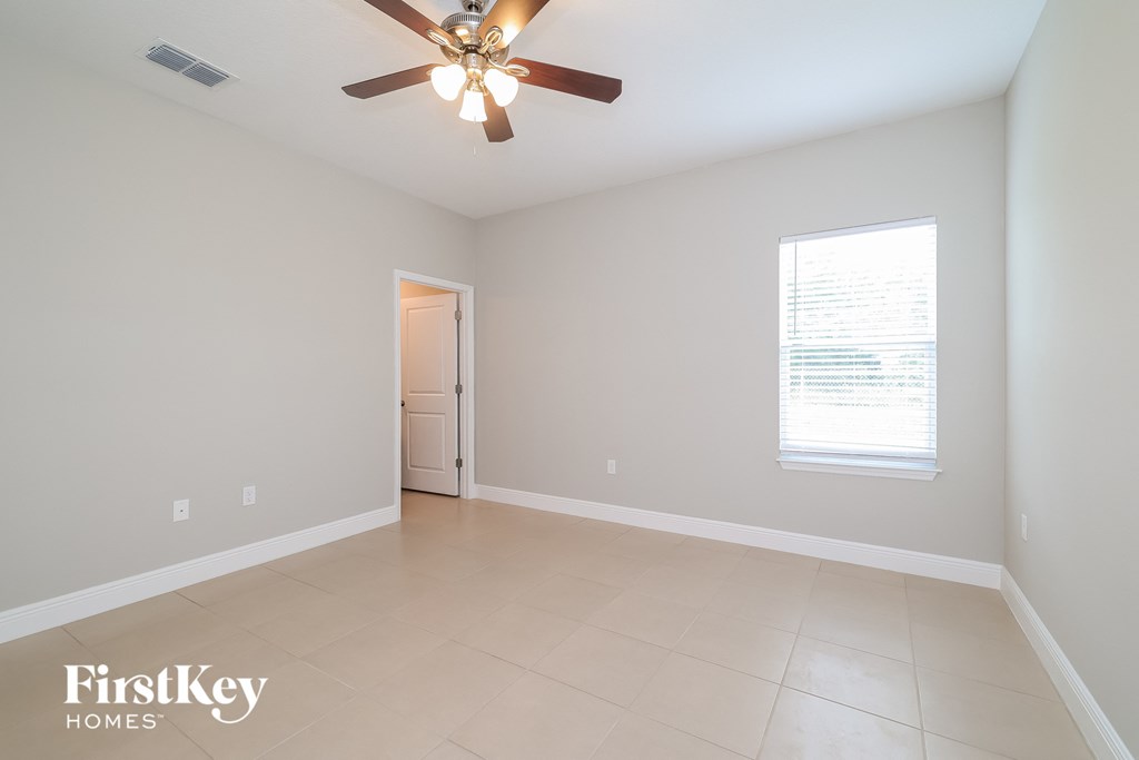 A room with a ceiling fan and a window with blinds.