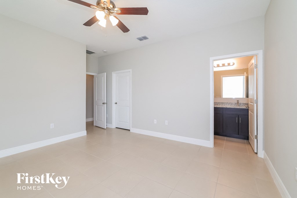 A spacious room with a ceiling fan and a door leading to a kitchen.