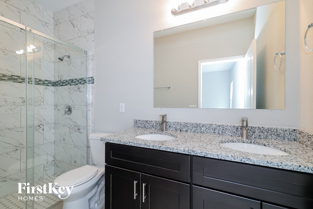 A bathroom with a marble shower and a white toilet.
