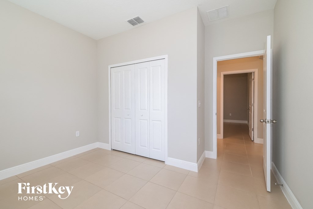 A room with a white door and a beige floor.