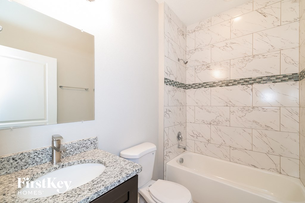 A bathroom with a marble tile wall and a white toilet.