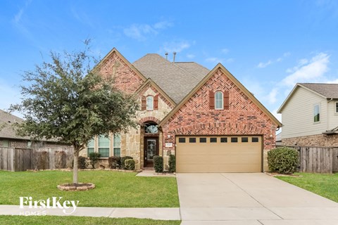 a brick house with a garage and a tree in the yard