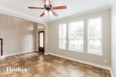 an empty living room with a ceiling fan and windows