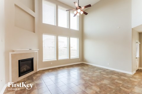 an empty living room with a fireplace and a ceiling fan
