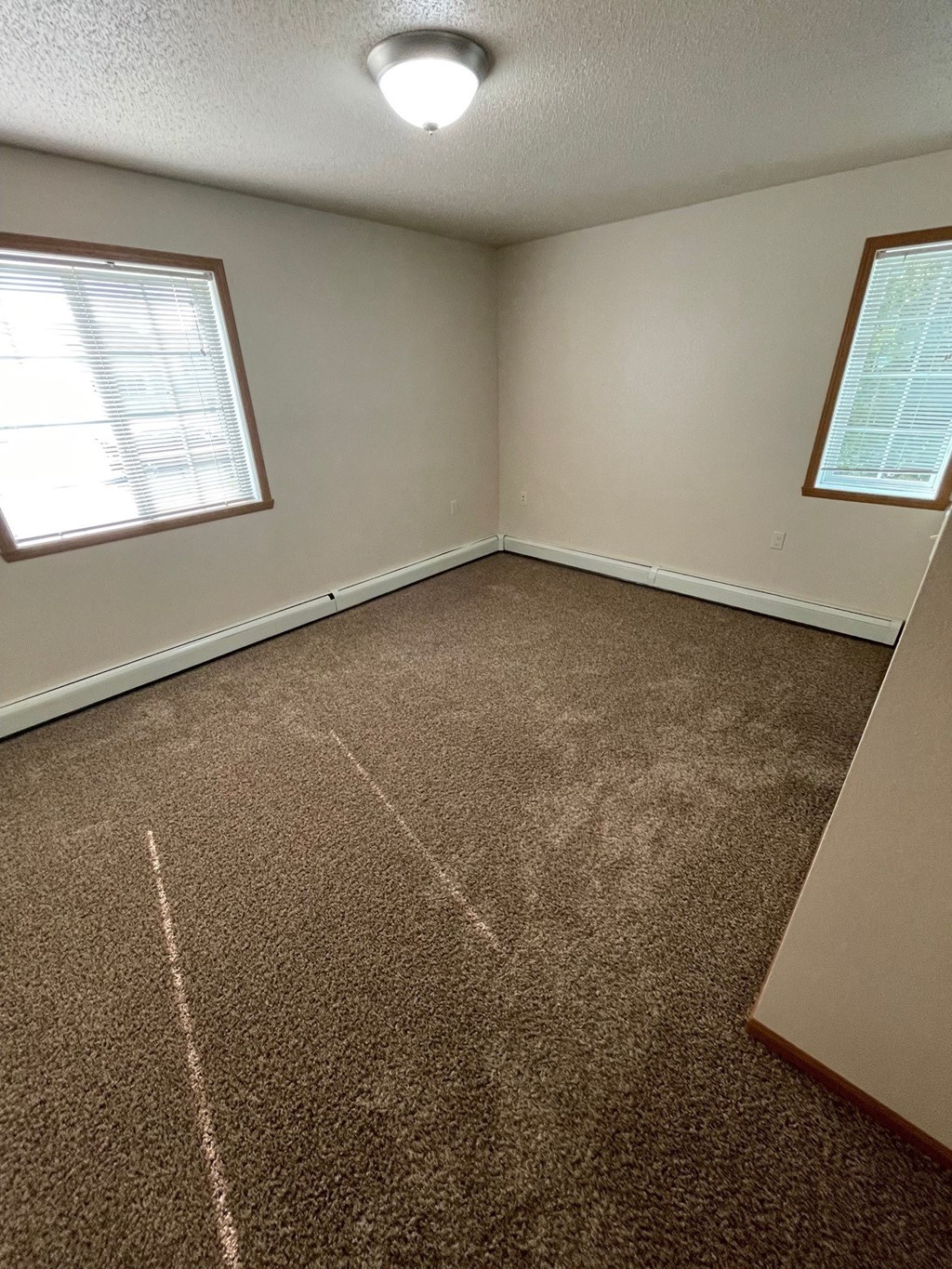 an empty room with carpet and two windows