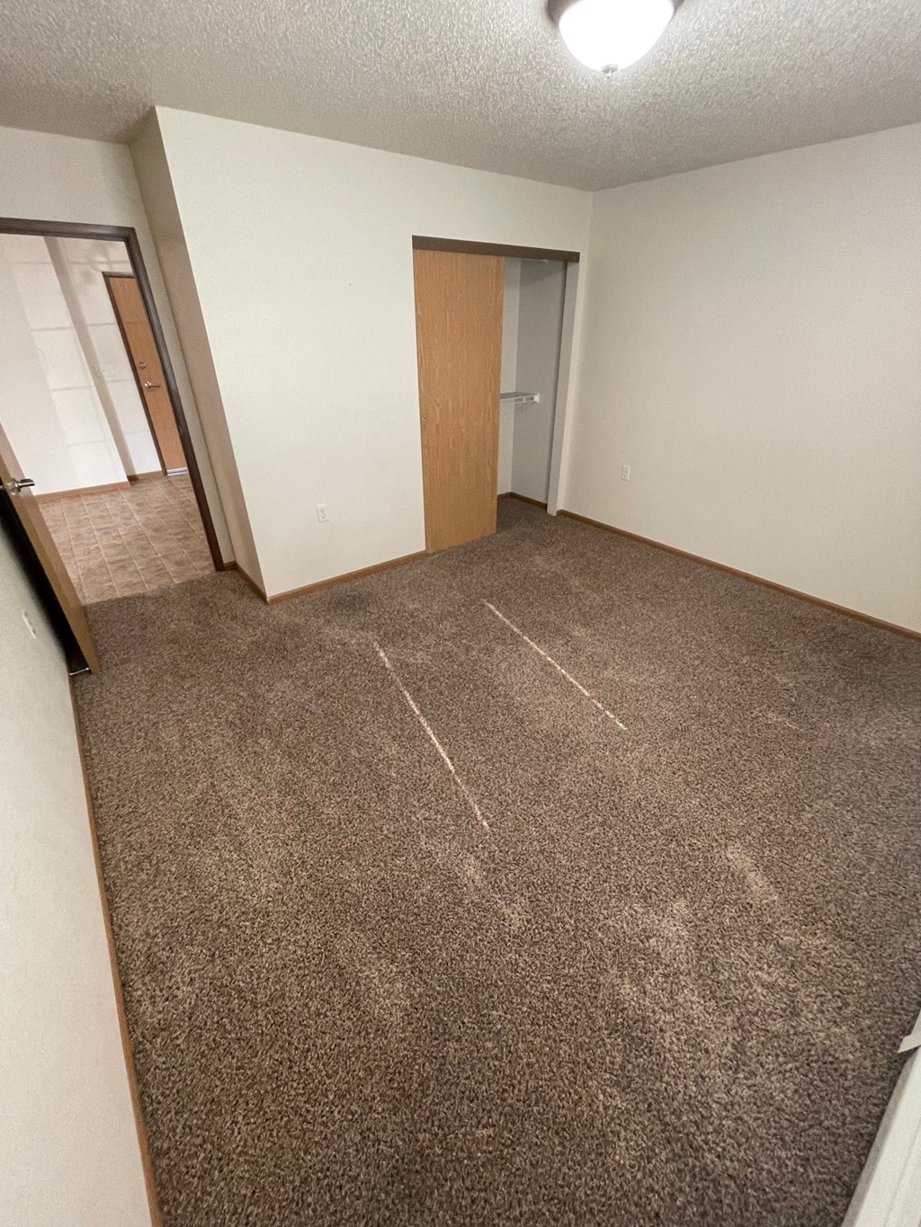 an empty living room with carpeting and a door to a bedroom