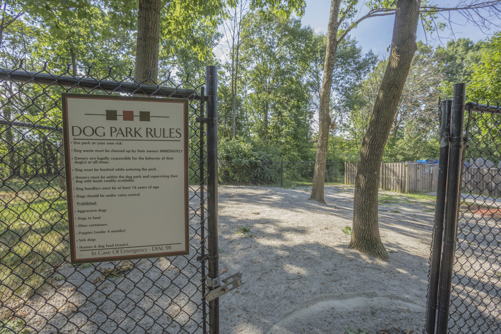 A sign that says Dog Park Rules is posted on a fence.