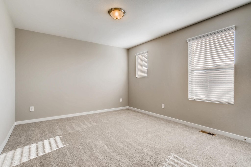 the spacious living room in a new home with a window and carpet
