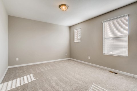 the spacious living room in a new home with a window and carpet