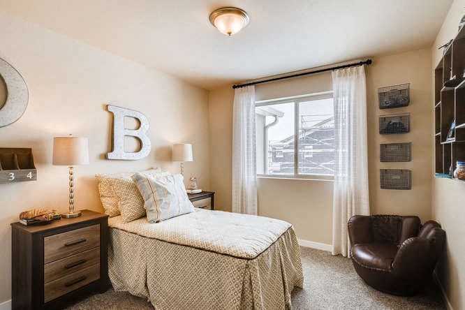 a bedroom with a bed and a chair and a window