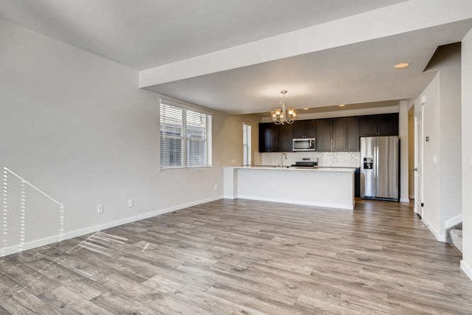 an empty living room and kitchen with a refrigerator