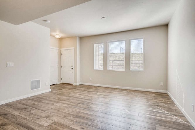 an empty living room with wood floors and a door