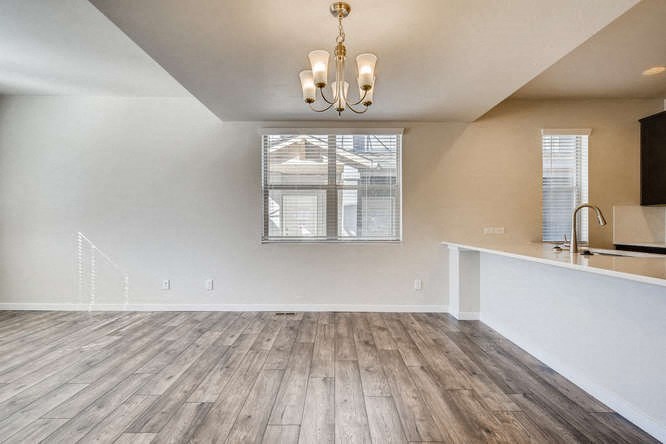 an empty living room with a kitchen and a window