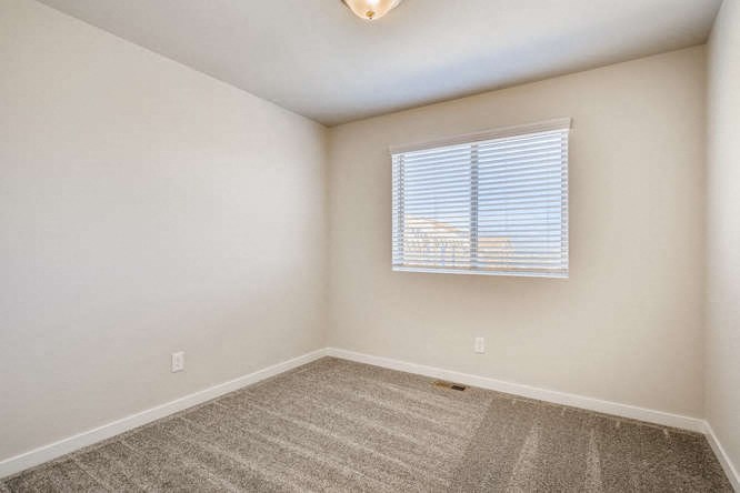 an empty room with a window and a carpet