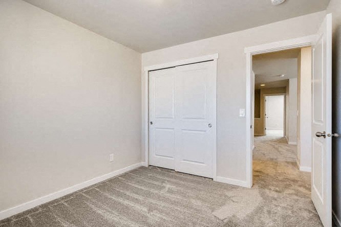 an empty bedroom with a white door and a hallway