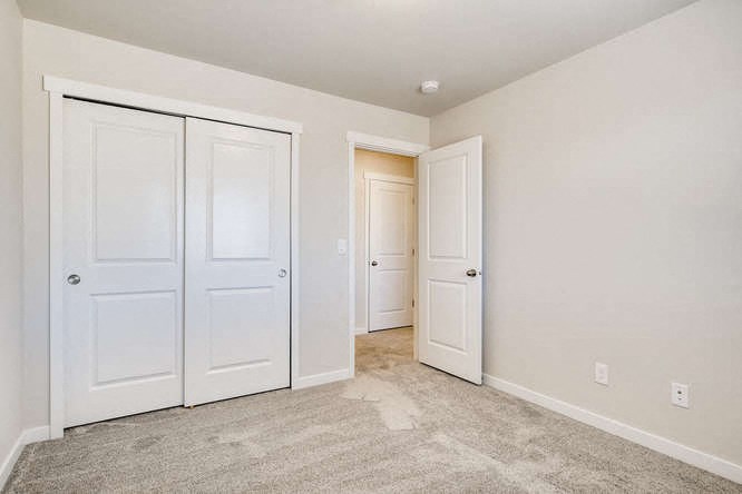 an empty bedroom with two doors and a closet