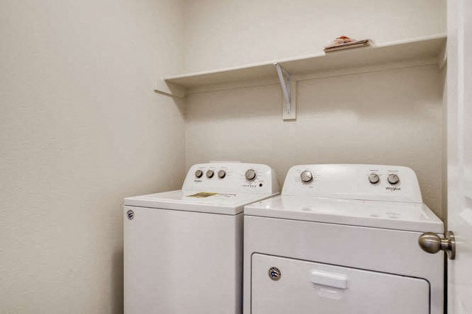 a white room with two washing machines and a shelf