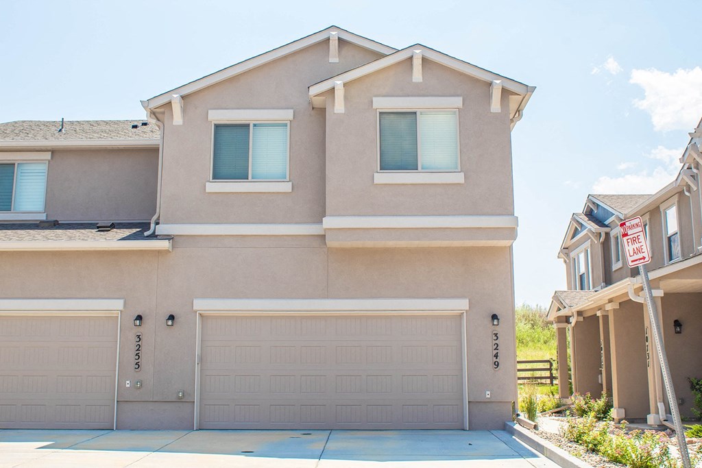 a beige house with two garage doors and a street sign