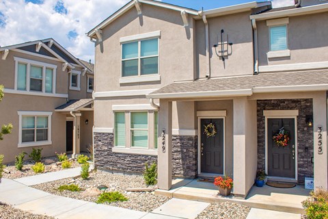 a beige house with a sidewalk in front of it