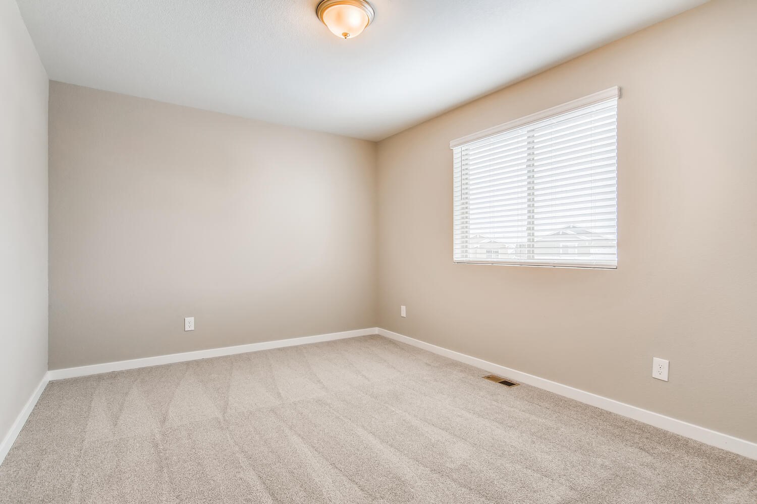 an empty room with a window and carpet