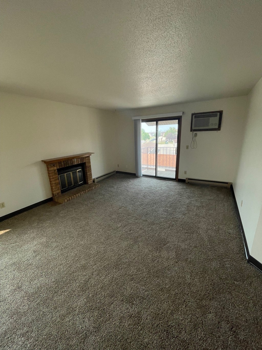 an empty living room with a fireplace and a sliding glass door