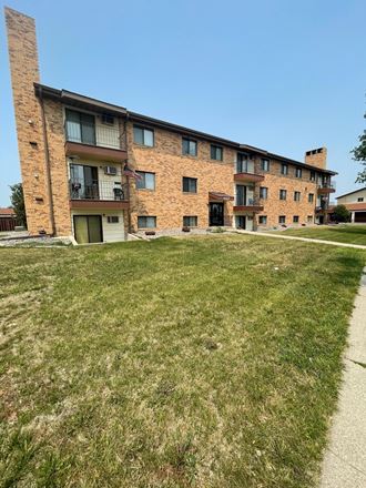 a large brick apartment building with a green lawn