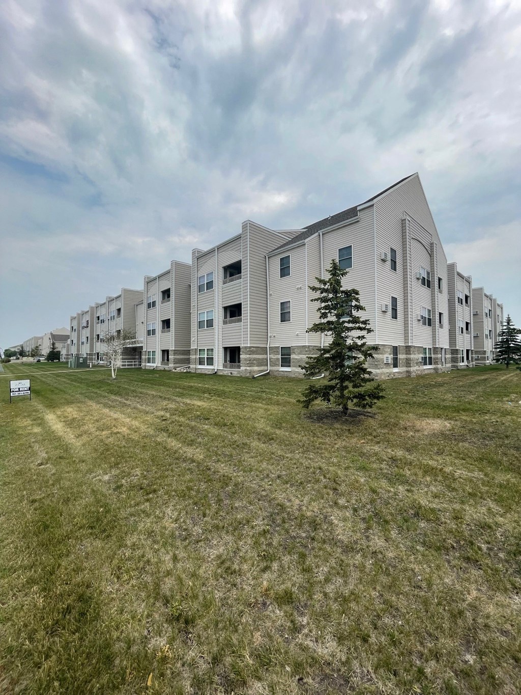 a view of the exterior of an apartment building on a grass field