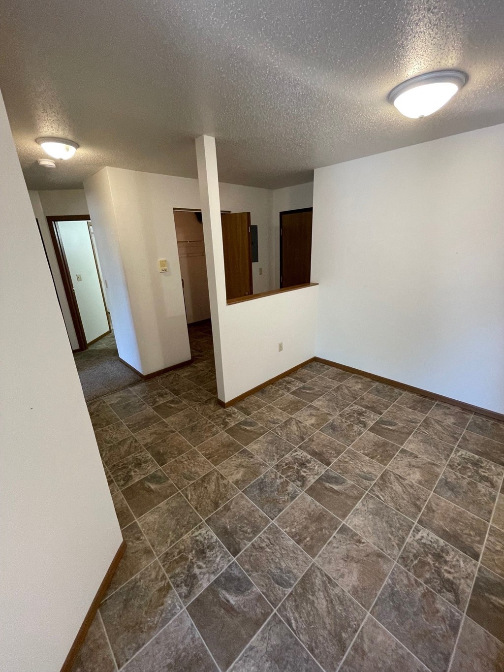 an empty living room with tile flooring and white walls
