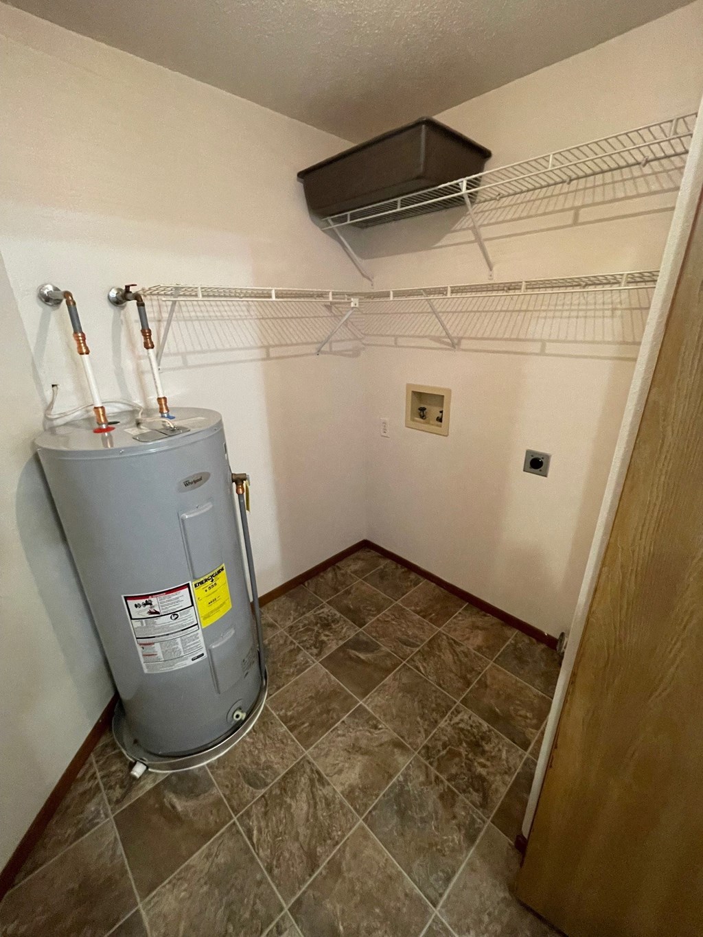 a small room with a water heater and a rack on the wall