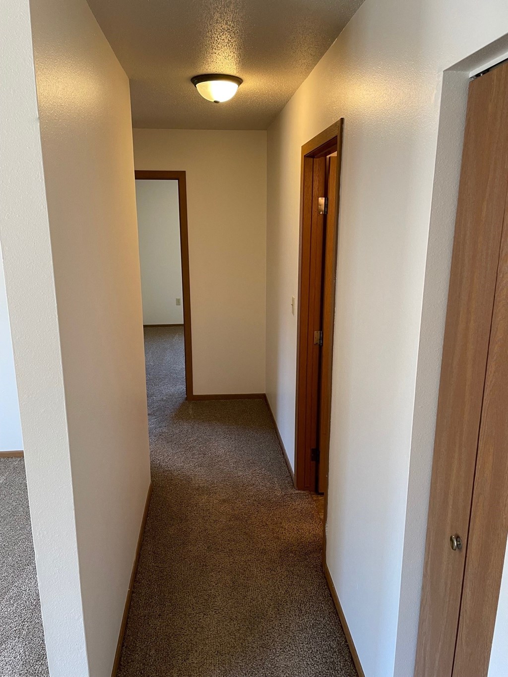 a hallway with a door to a bedroom and a hall way to a bathroom and