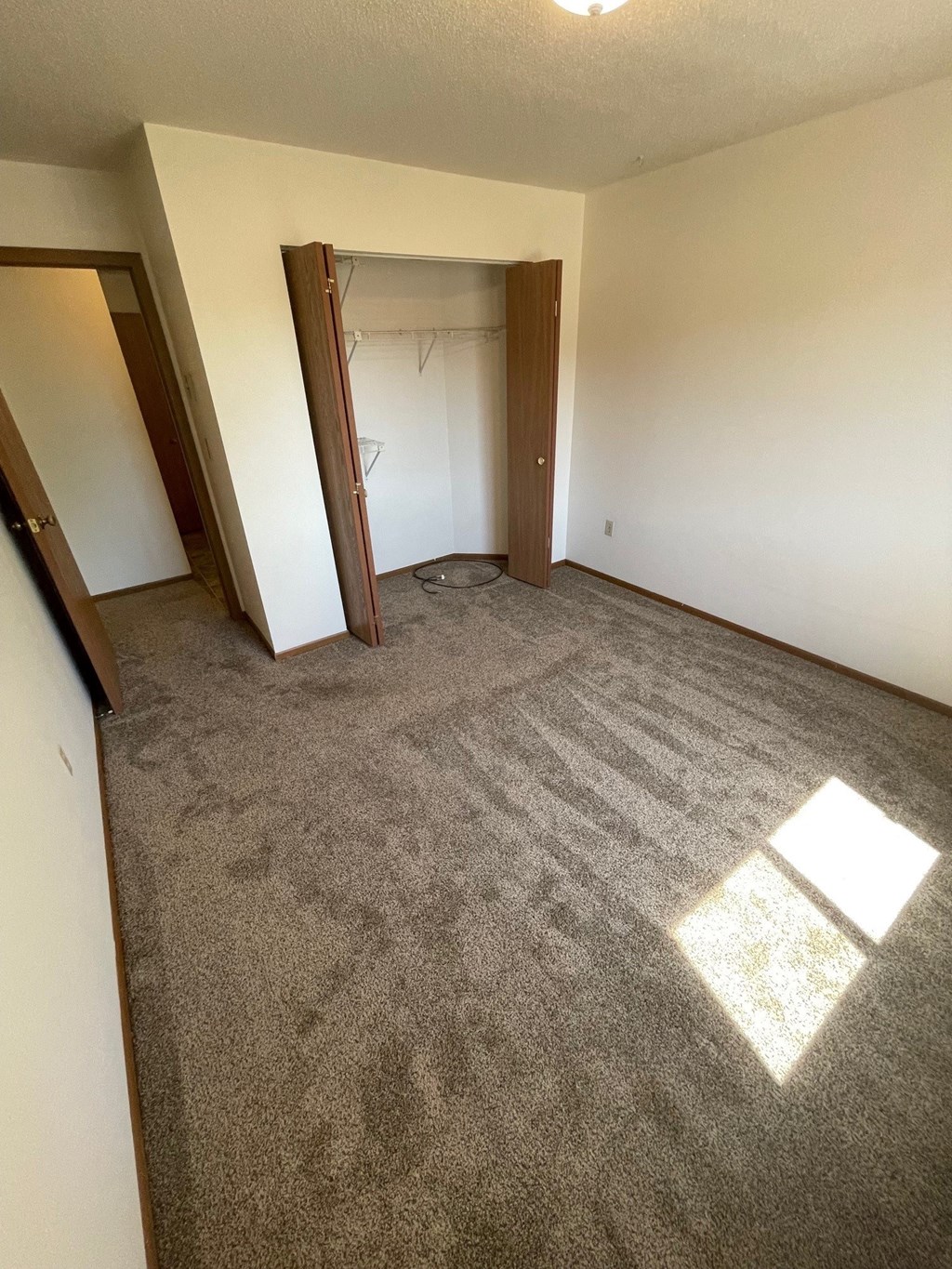 an empty living room with carpet and a door to a closet
