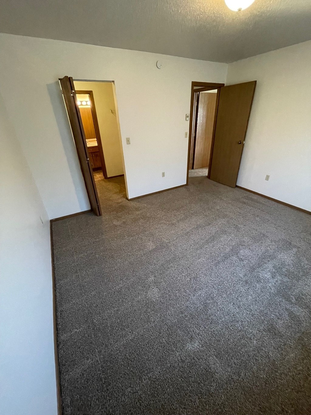 an empty room with a carpeted floor and two doors