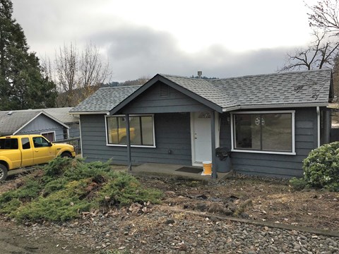 A house with a grey roof and a yellow truck parked in front.