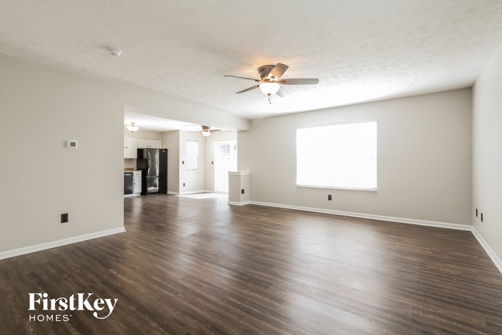 an empty living room with wood floors and a ceiling fan